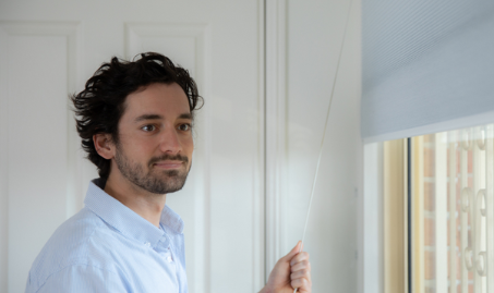 Man closing blinds to save energy