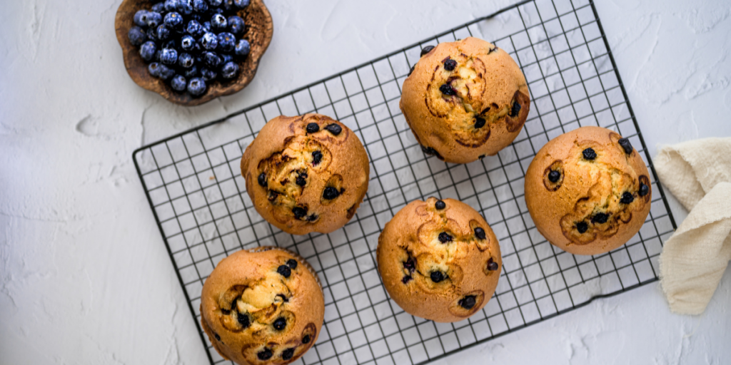 Muffins on a tray with a bowl of blueberries