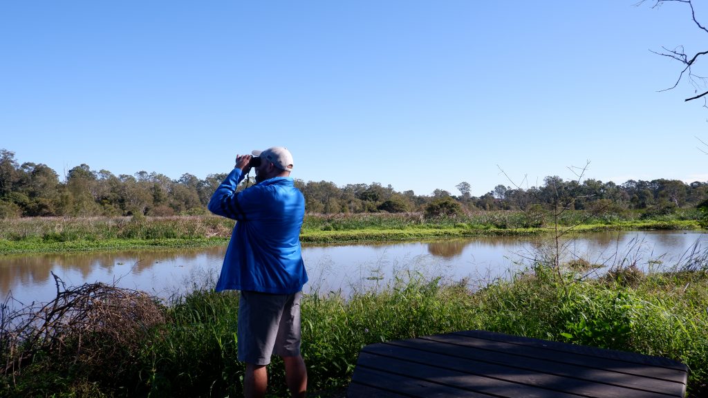 Man overlooking lake through binoculars