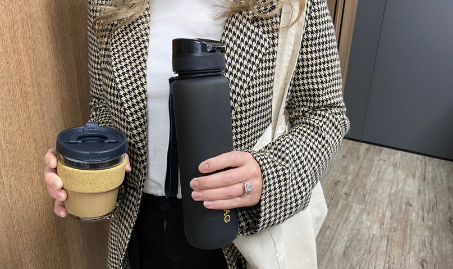 A woman holding a keep cup and drink bottle