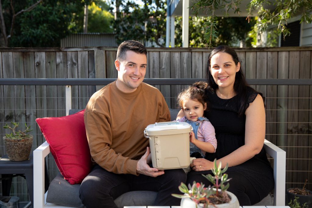 The Jackson family sitting on their back deck holding a compost caddy