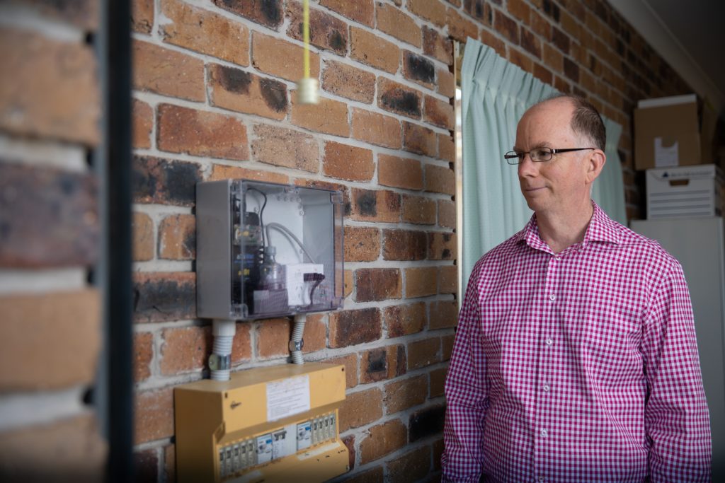 Peter Blumke looking at his PhiSaver monitoring device, connected to his switchbox.