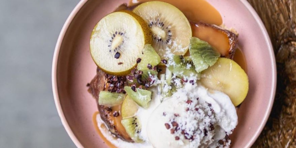 A pink bowl full of fruit and yoghurt