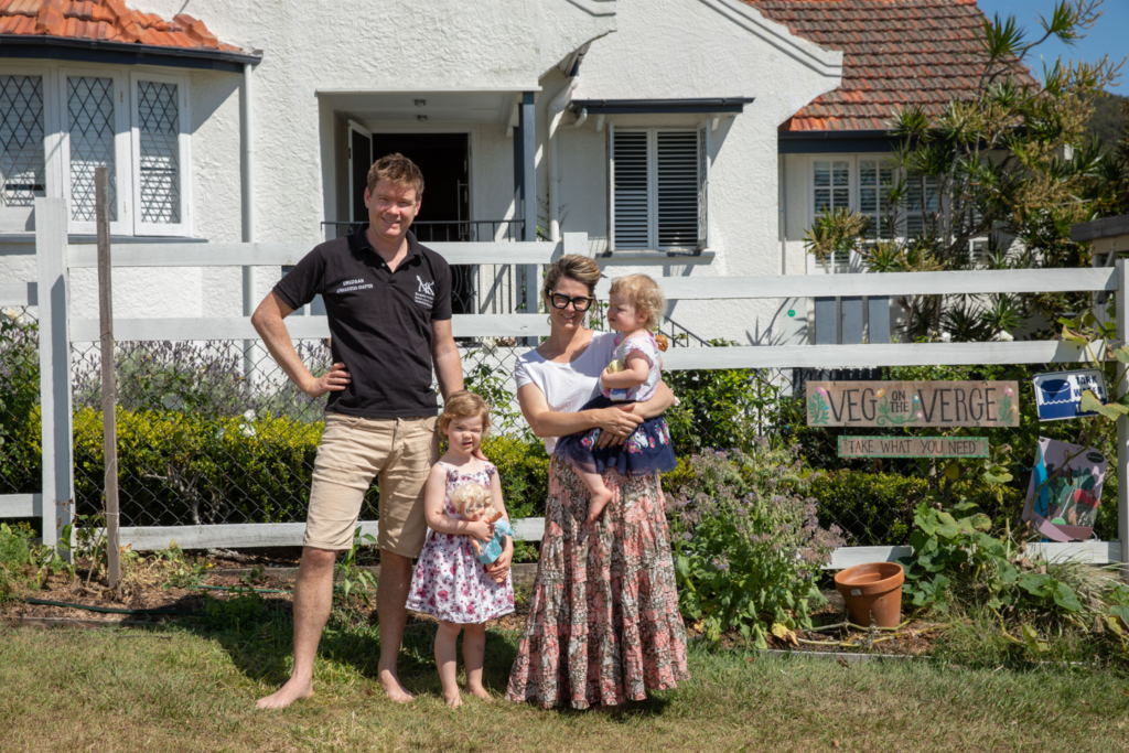 The Churton family standing in their front yard outside their home on a sunny day, smiling into the camera