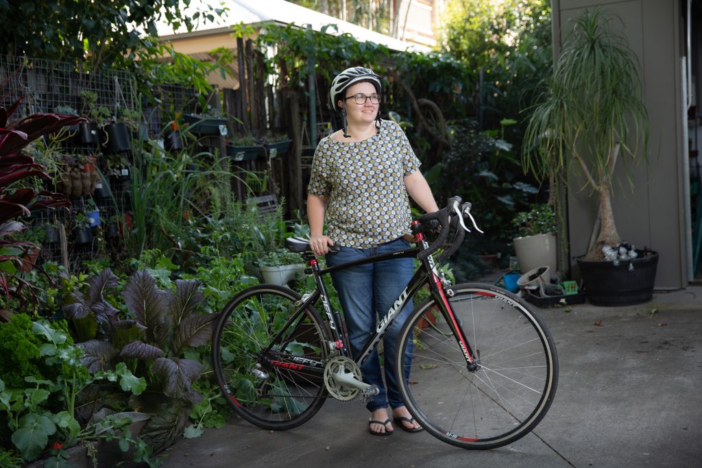 Miriam standing holding her bicycle with her helmet on.