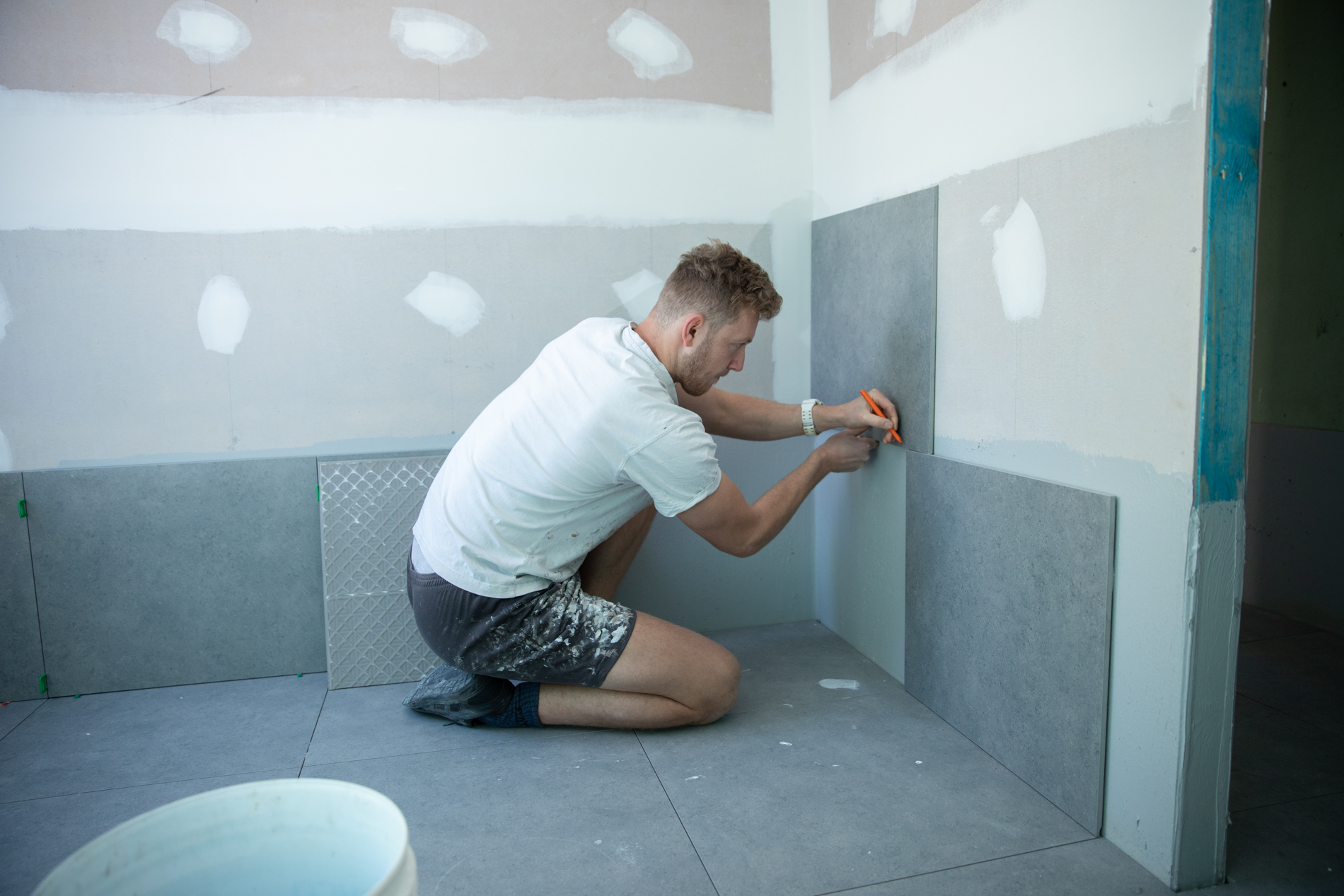 Builder installing tiles as skirting to above the estimated flood level