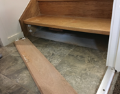 Image of wooden stair with the first vertical panel popped out to make cavity underneath accessible for water to escape.