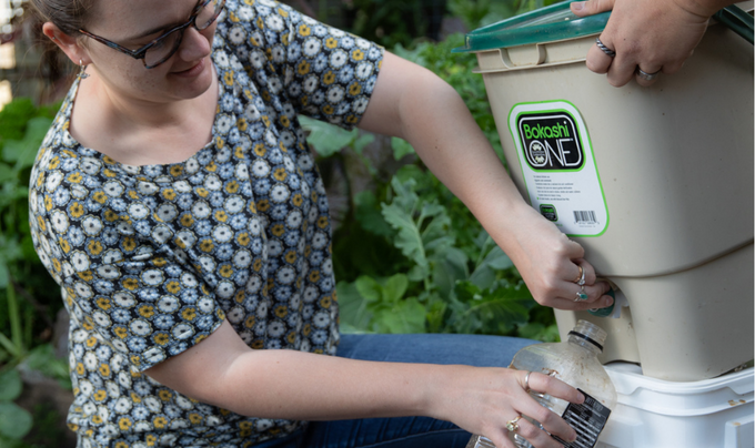 Woman extracting compost fertiliser tea from her bokashi bin