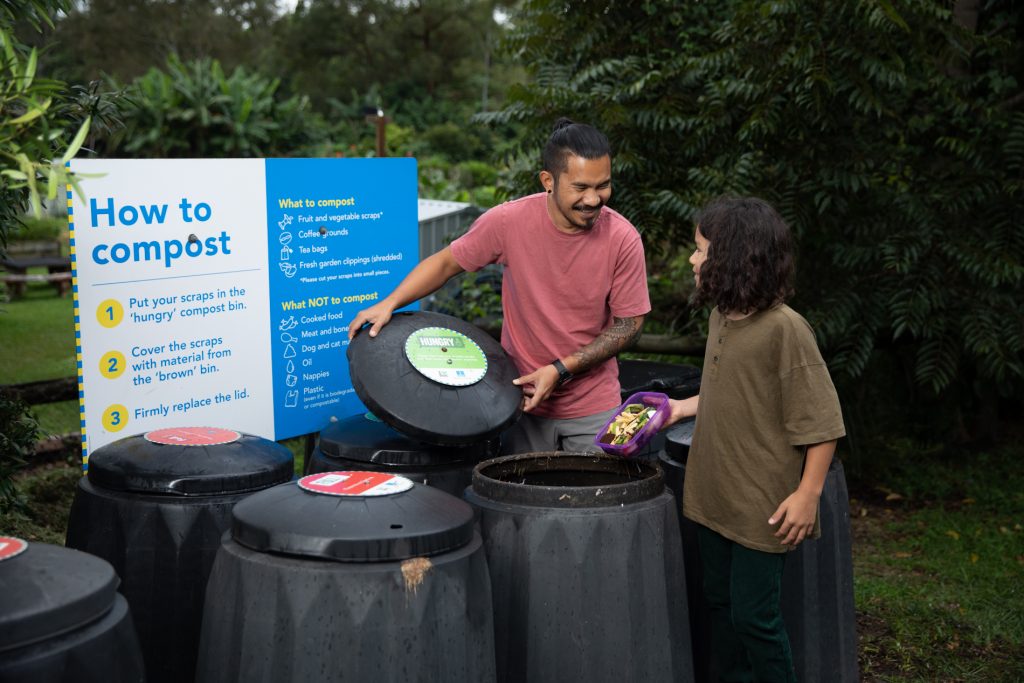man and child using community compost bins