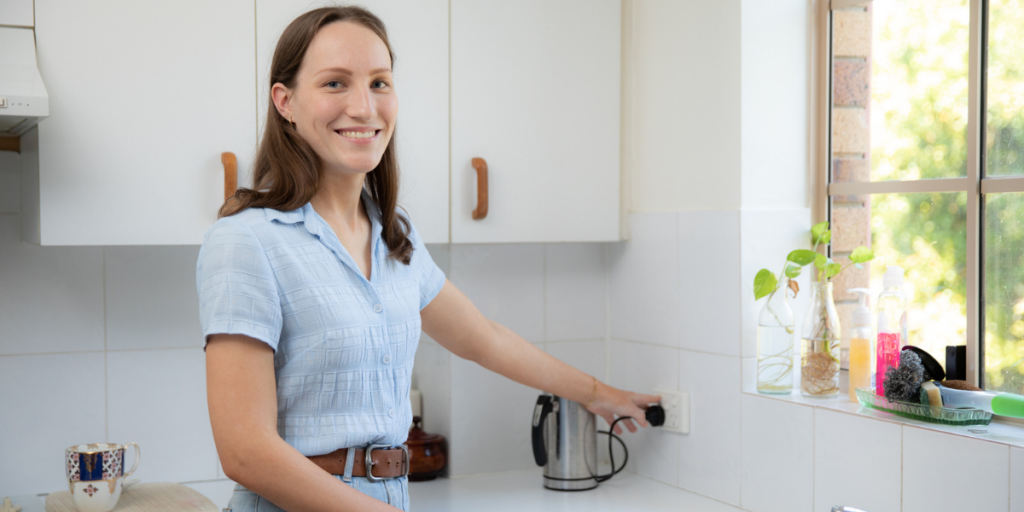 Laura switching off kettle in her kitchen