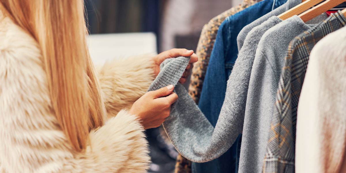 Woman looking through clothes and assessing the sleeve of a jumper/sweater.