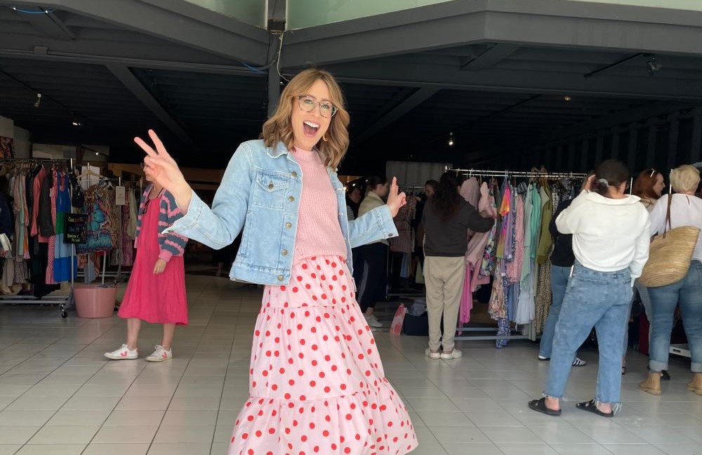 BSA staff member posing and smiling into the camera while standing in front of an indoor clothes market.