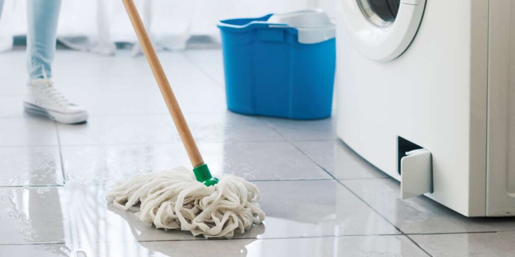 A person mopping up leaks near a washing machine