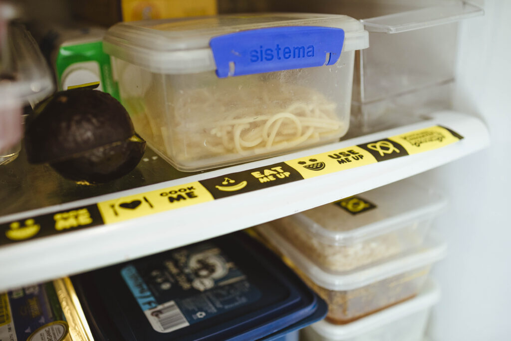 food containers in fridge with 'use it up' labels on them.