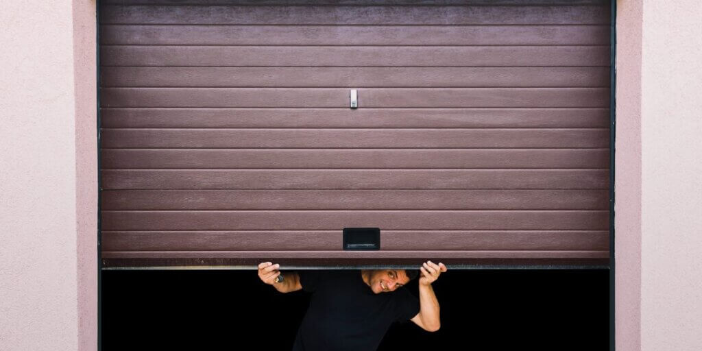 Garage door half open with person peaking out underneath