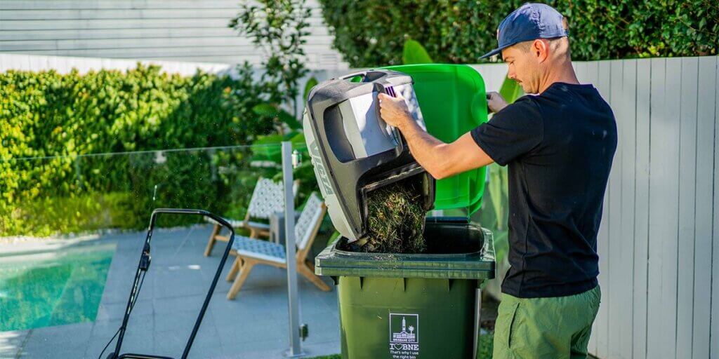 Man emptying grass clippings into bin