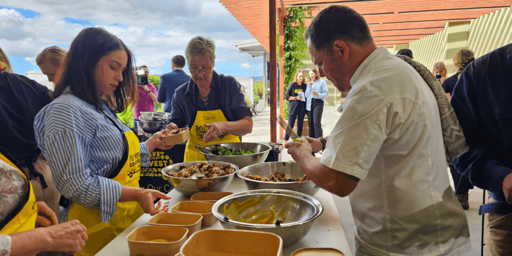 A chef and two volunteers preparing meals with reclaimed food, showcasing sustainable cooking practices.