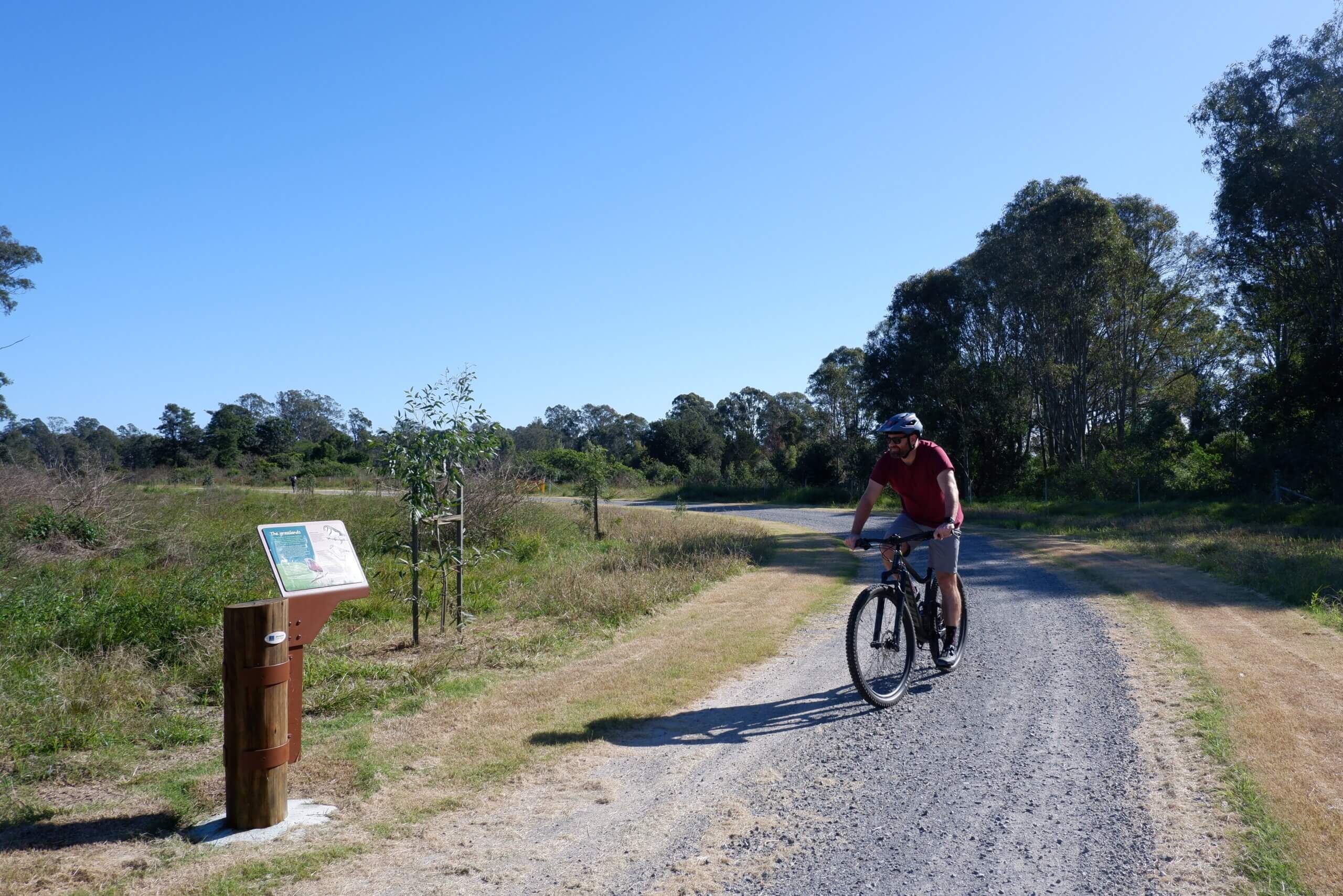 Man riding bicycle through gravel path.